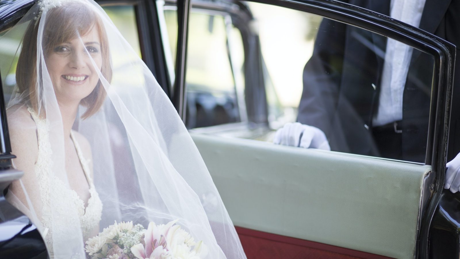 Smiling bride getting out of car before her wedding